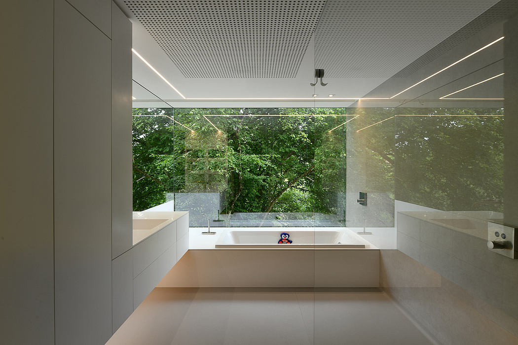Minimalist bathroom with glass wall overlooking lush greenery outside.