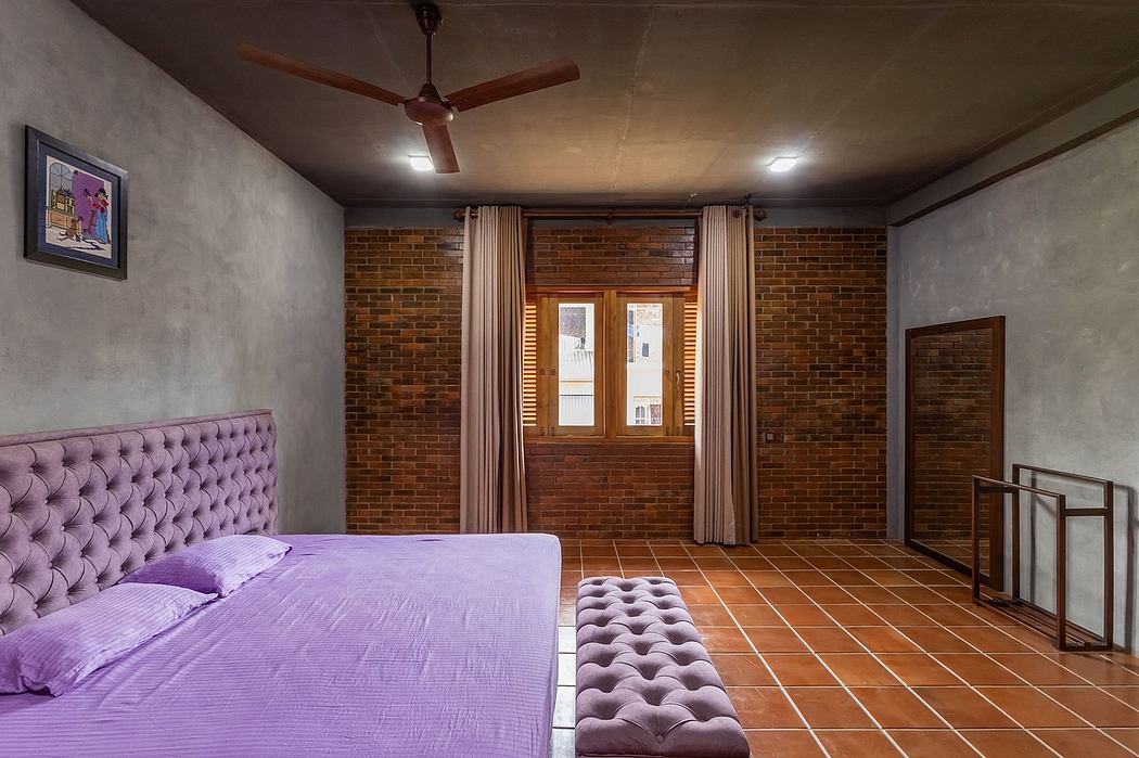 Rustic bedroom with exposed brick walls, hardwood floors, and a plush purple tufted headboard.