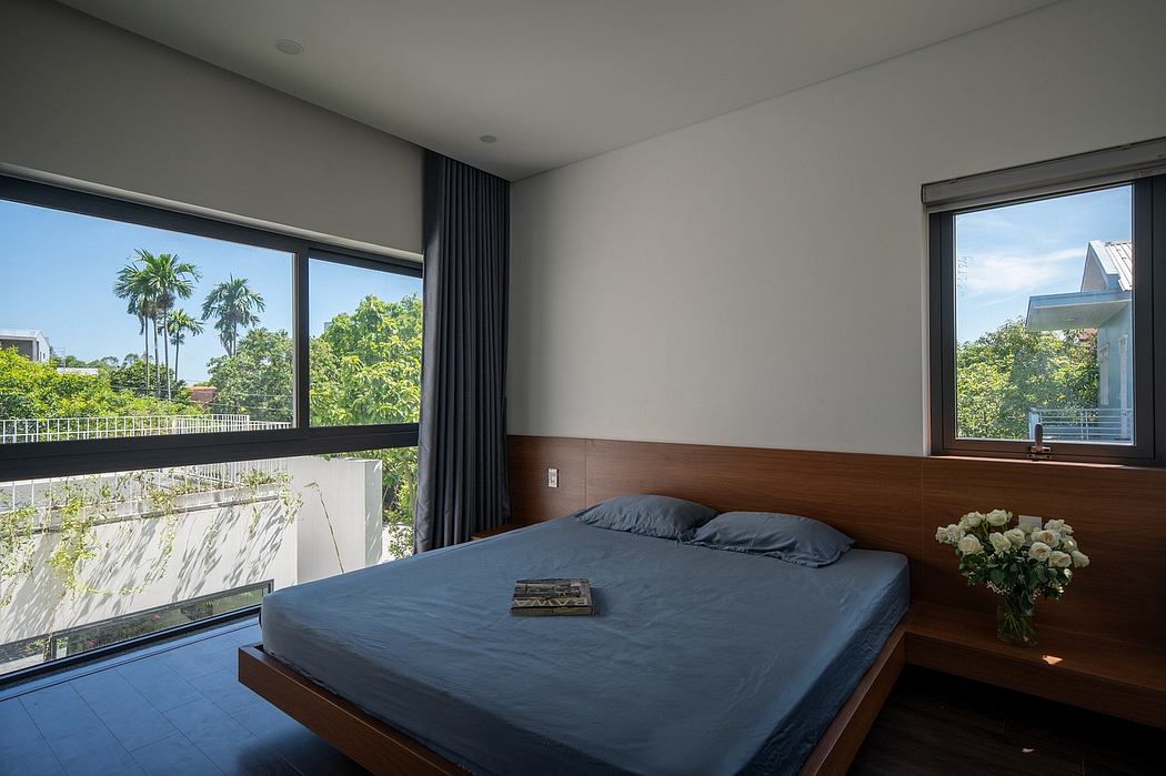 Minimalist bedroom with floor-to-ceiling windows, wooden headboard, and lush outdoor view.