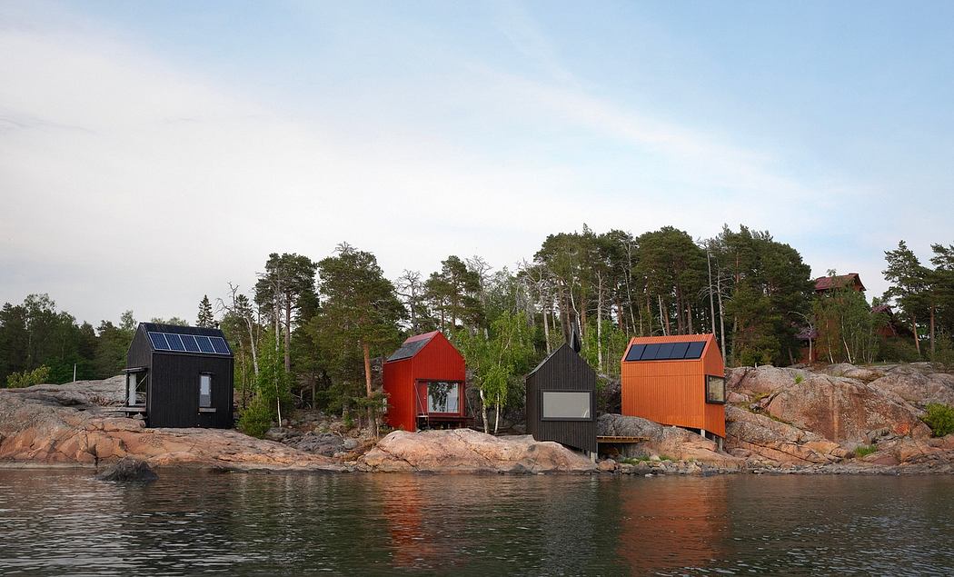 Small cabins with solar panels nestled in the rocky shoreline of a lake, surrounded by pine trees.