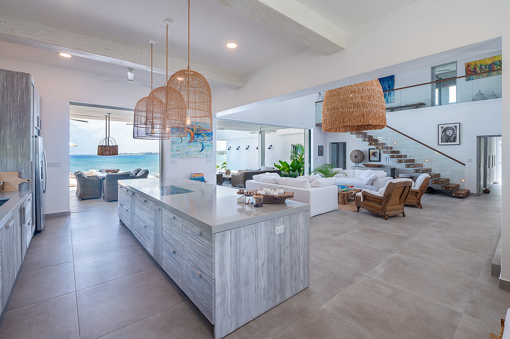 Spacious open-concept living area with modern kitchen island, rattan lighting, and ocean view.