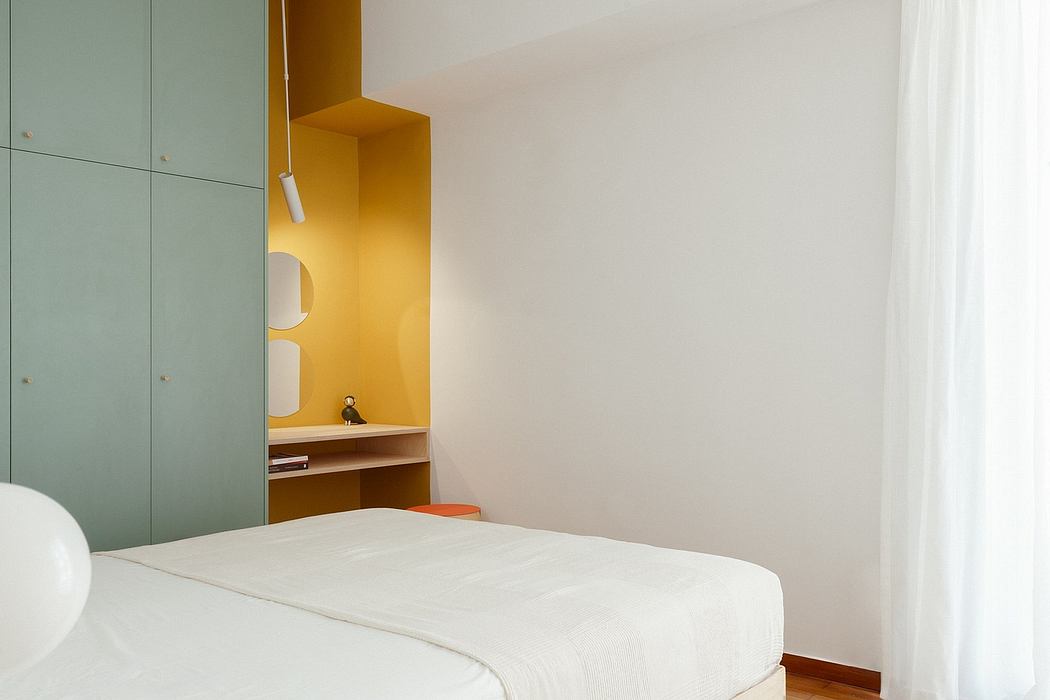 Minimalist bedroom with built-in green cabinets, warm orange accents, and a simple bed.