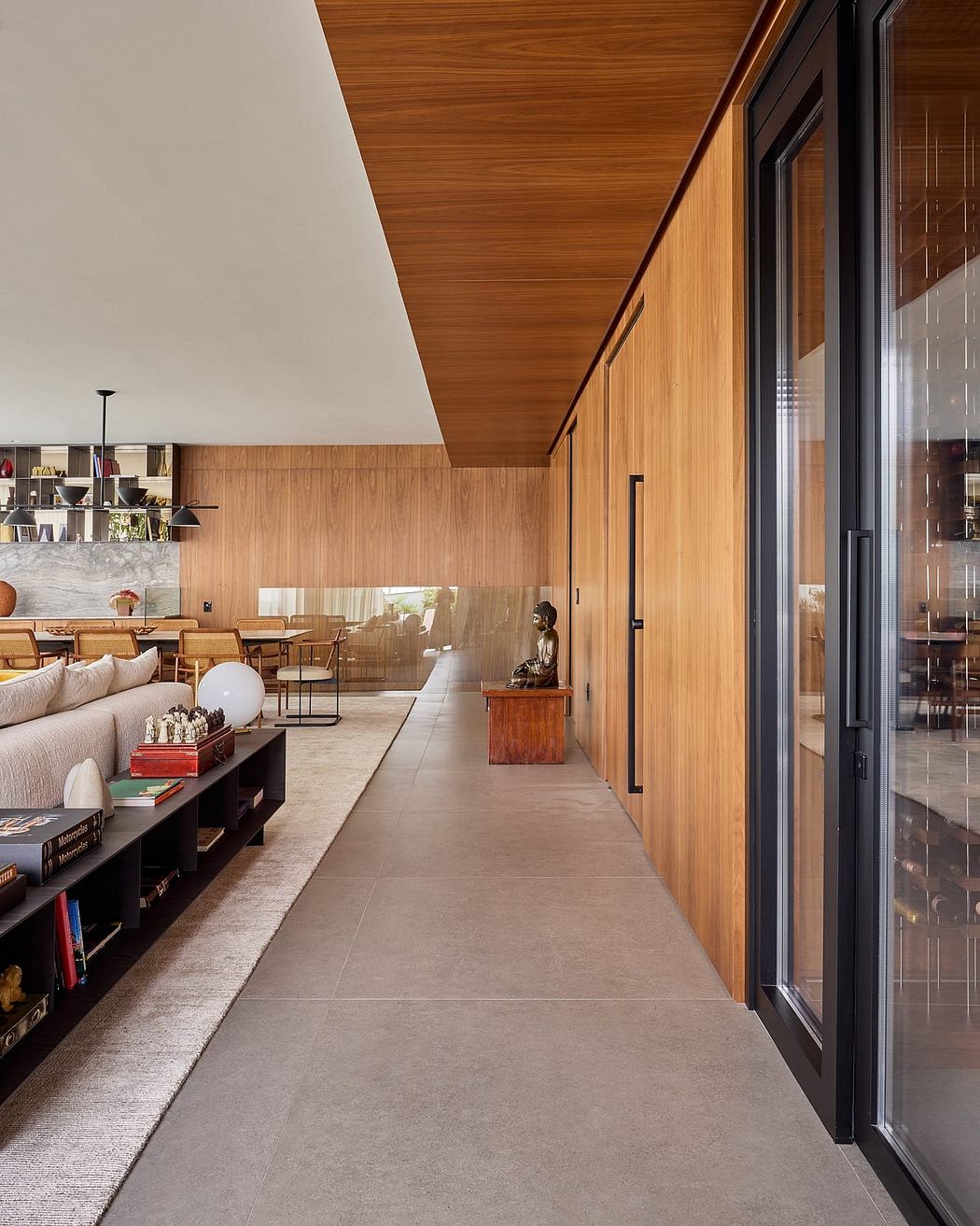 Warm-toned wood paneling, concrete floors, and built-in shelving create a modern, minimalist aesthetic.