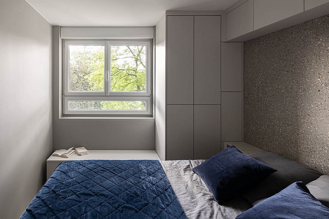 Modern minimalist bedroom with built-in gray cabinetry, large window, and textured accent wall.