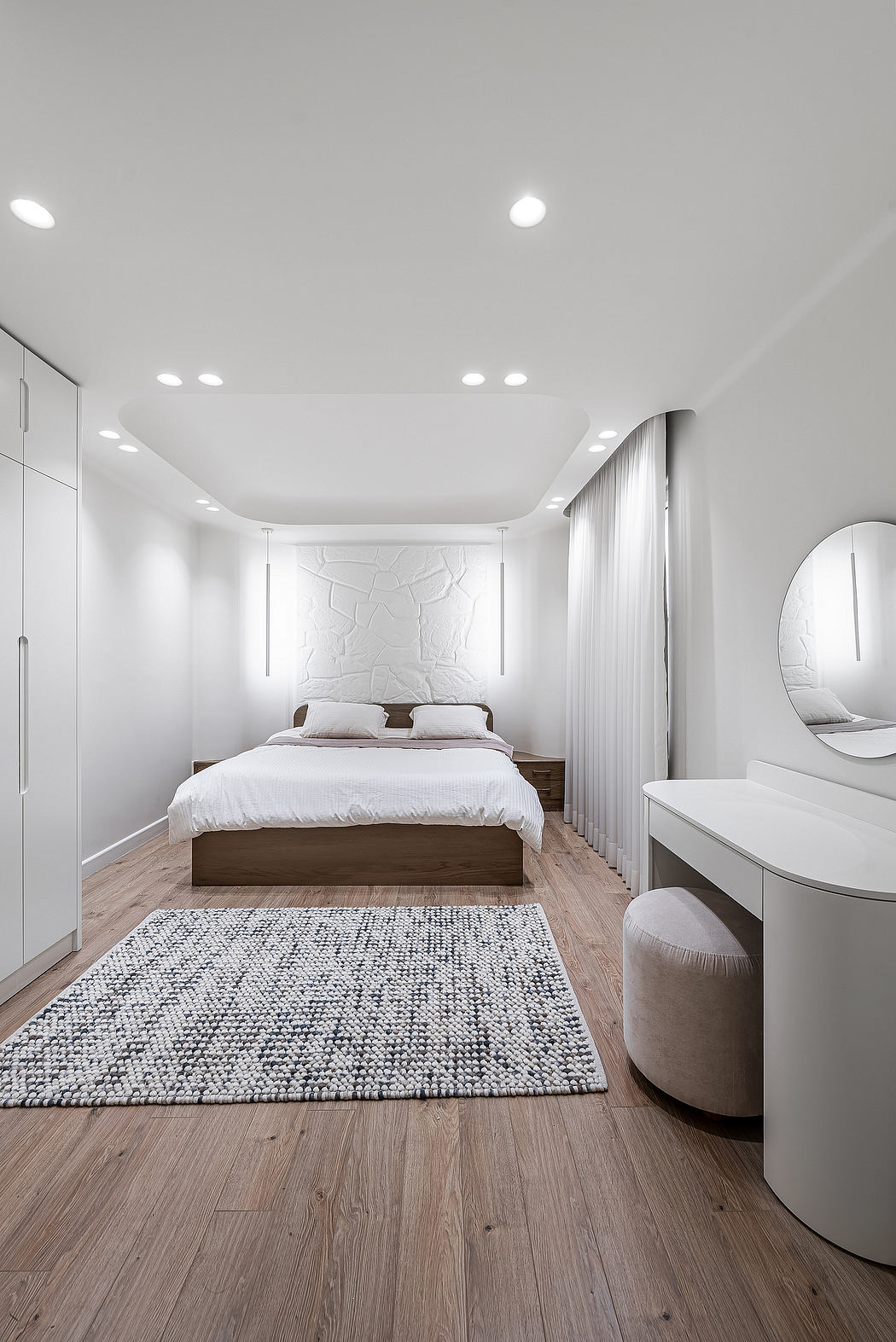 Modern bedroom with clean lines, recessed lighting, and textured accent wall.