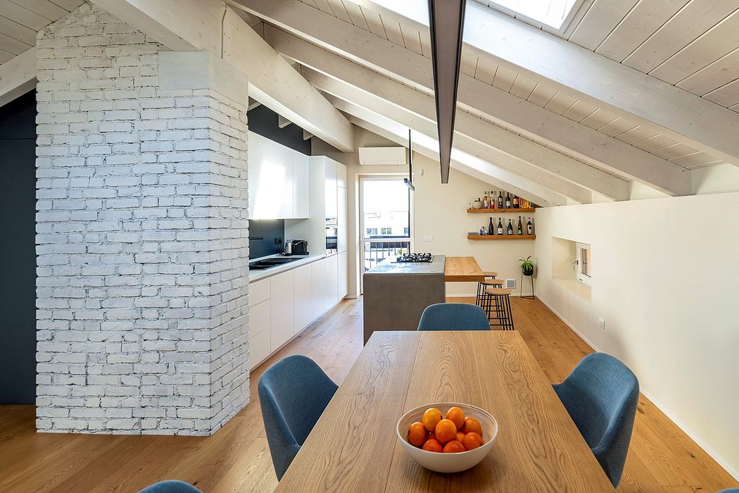Open-concept kitchen and dining area with exposed wood beams, white brick wall, and modern furniture.