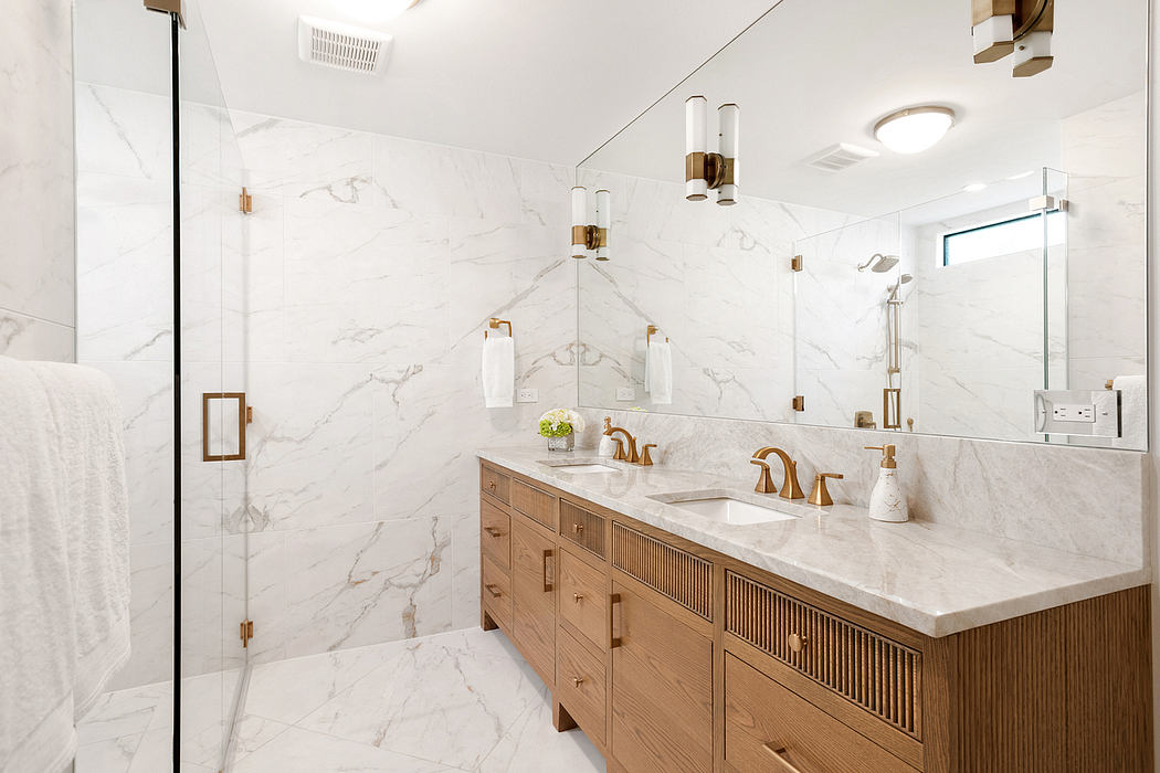 Luxurious bathroom with marble-tile walls, wooden vanity, and brass fixtures.