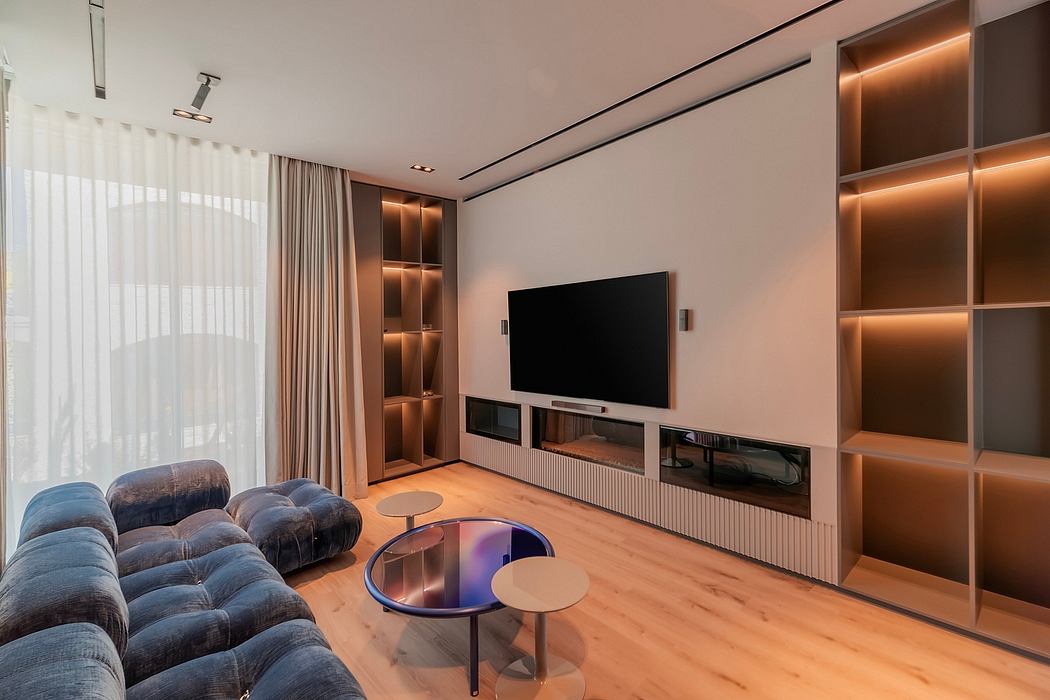 A modern living room with sleek, built-in cabinetry, plush seating, and a large TV.
