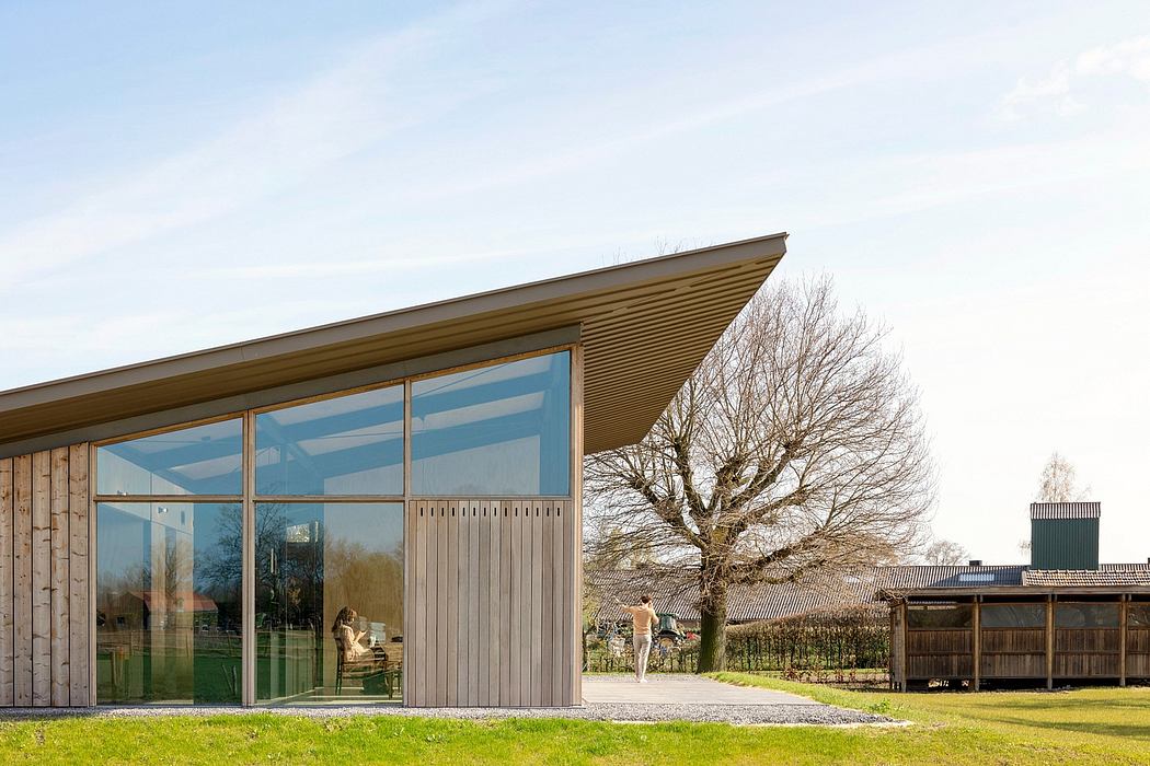 Wooden-paneled exterior with large glass windows overlooking a grassy yard and bare tree.