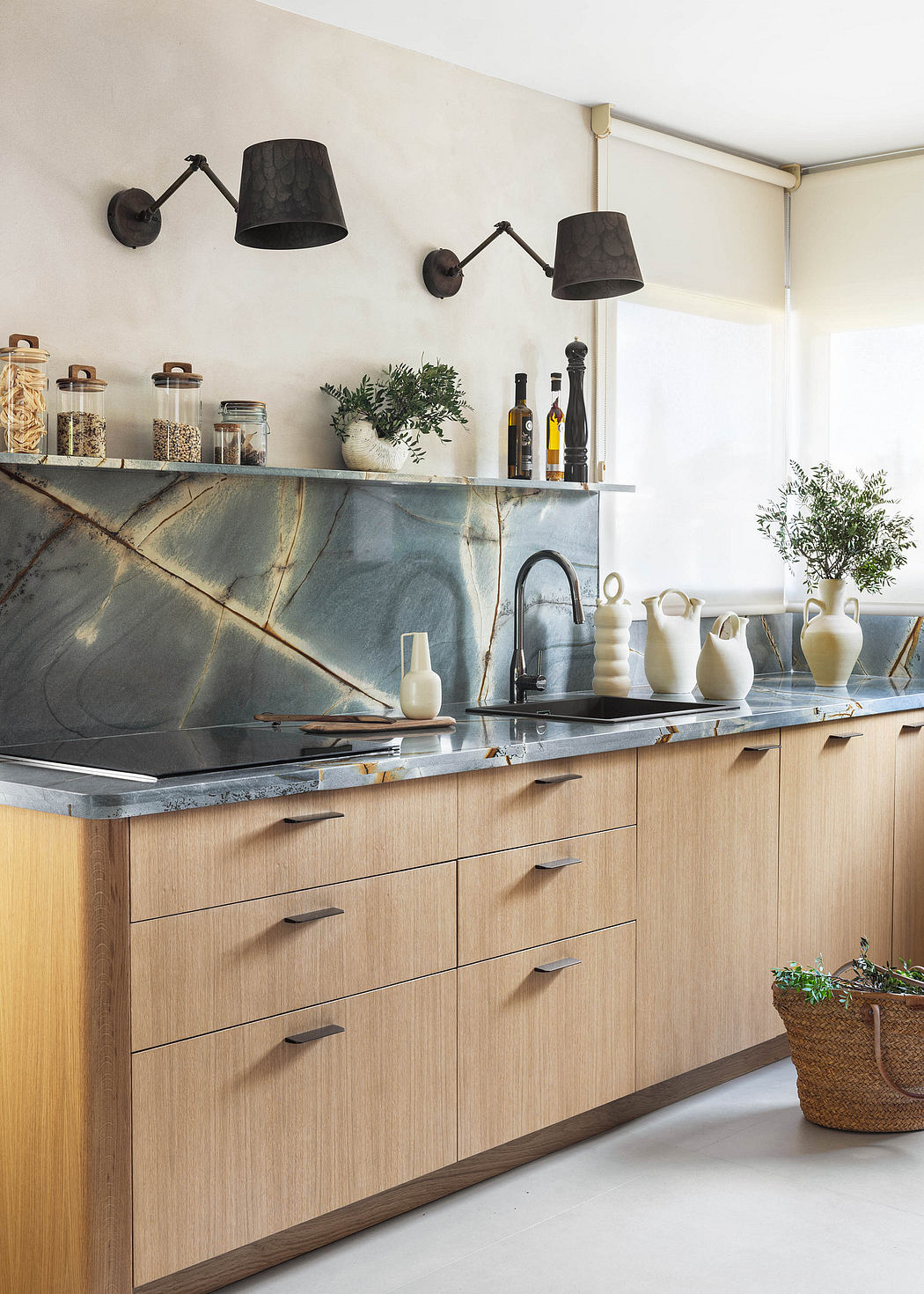 This modern kitchen features a sleek wood and granite countertop, black sconce lights, and decorative objects.