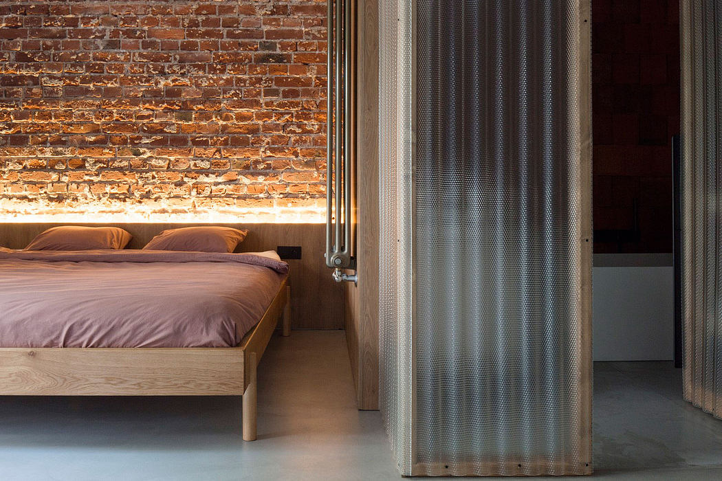 Rustic bedroom with exposed brick wall, wooden bed frame, and sheer curtain partition.