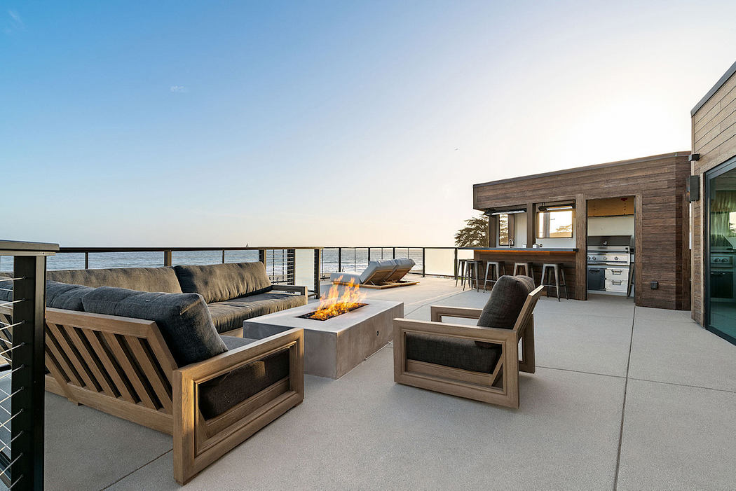 Stunning open-concept patio design with modern wood furnishings, fire pit, and ocean views.