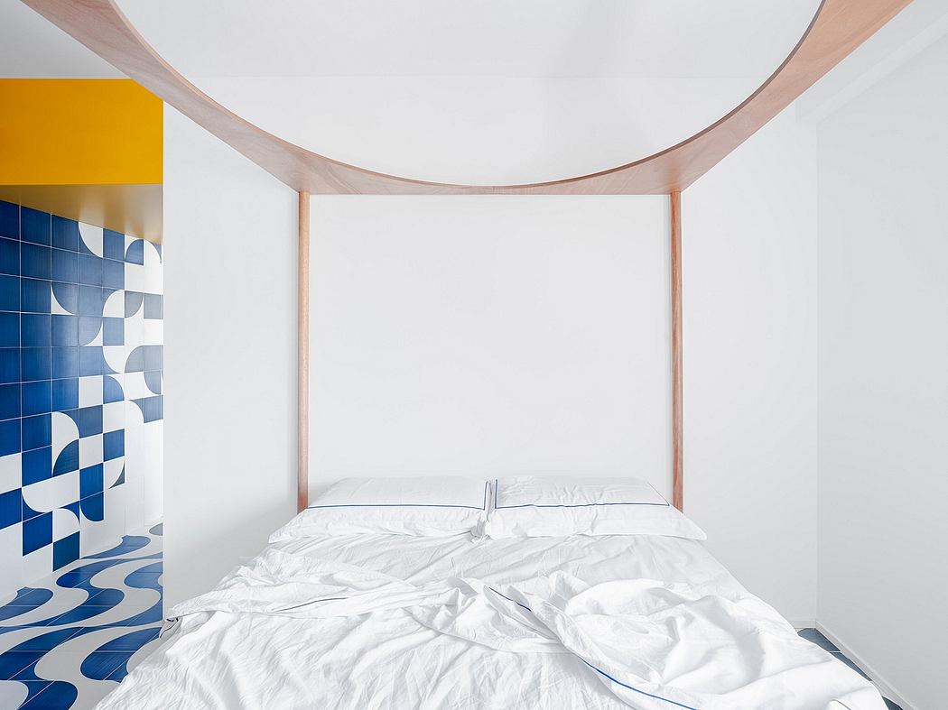 Minimalist bedroom with curved wooden bed frame, vibrant blue tile wall, and warm accent lighting.