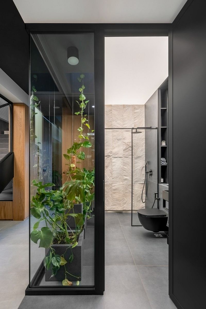 A modern bathroom with minimalist design, featuring a glass-enclosed shower and potted plants.