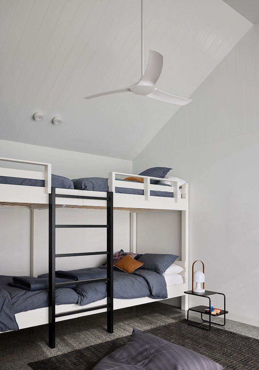 Minimalist bunk bed setup with geometric ceiling fan, monochromatic bedding, and modern decor.