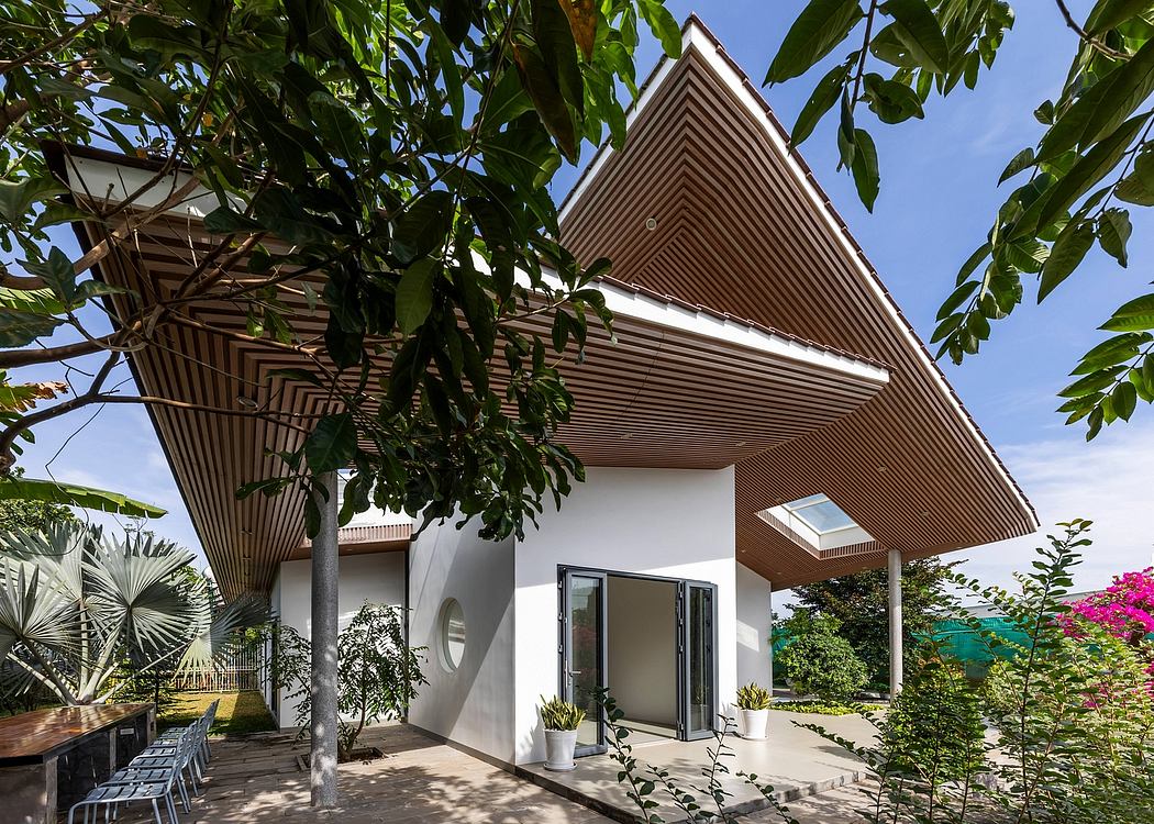 A modern, triangular-roofed structure with distinctive wooden cladding nestled among lush greenery.