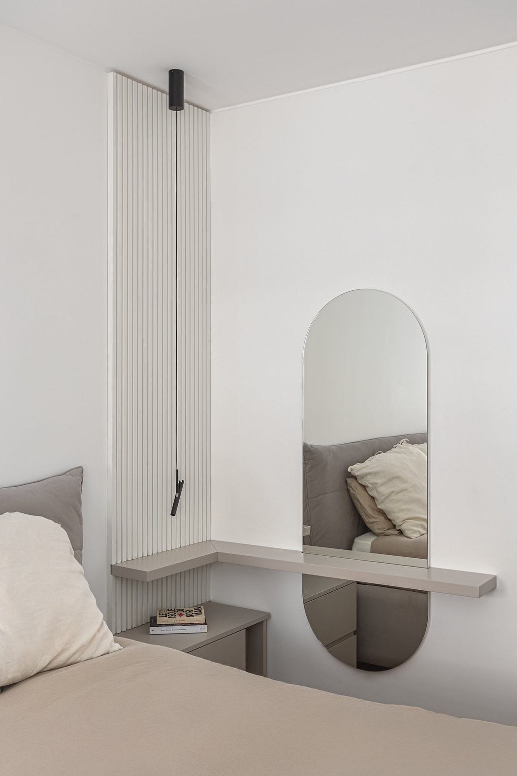 Minimalist bedroom with arched mirror, built-in shelving, and vertical radiator panels.
