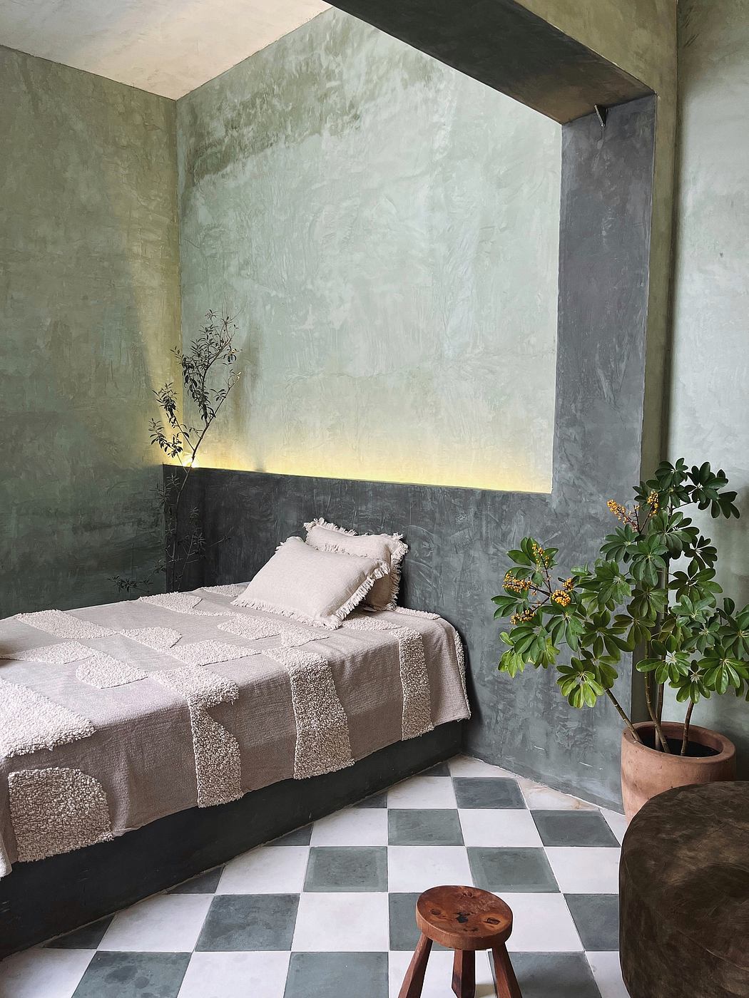 Cozy bedroom with textured green walls, checkered tile floor, and potted plant.