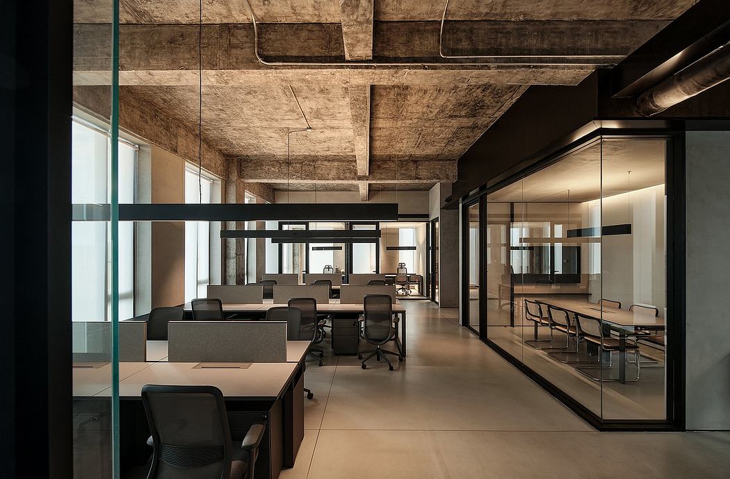 Open-concept office with exposed wooden beams, glass partitions, and modern furniture.