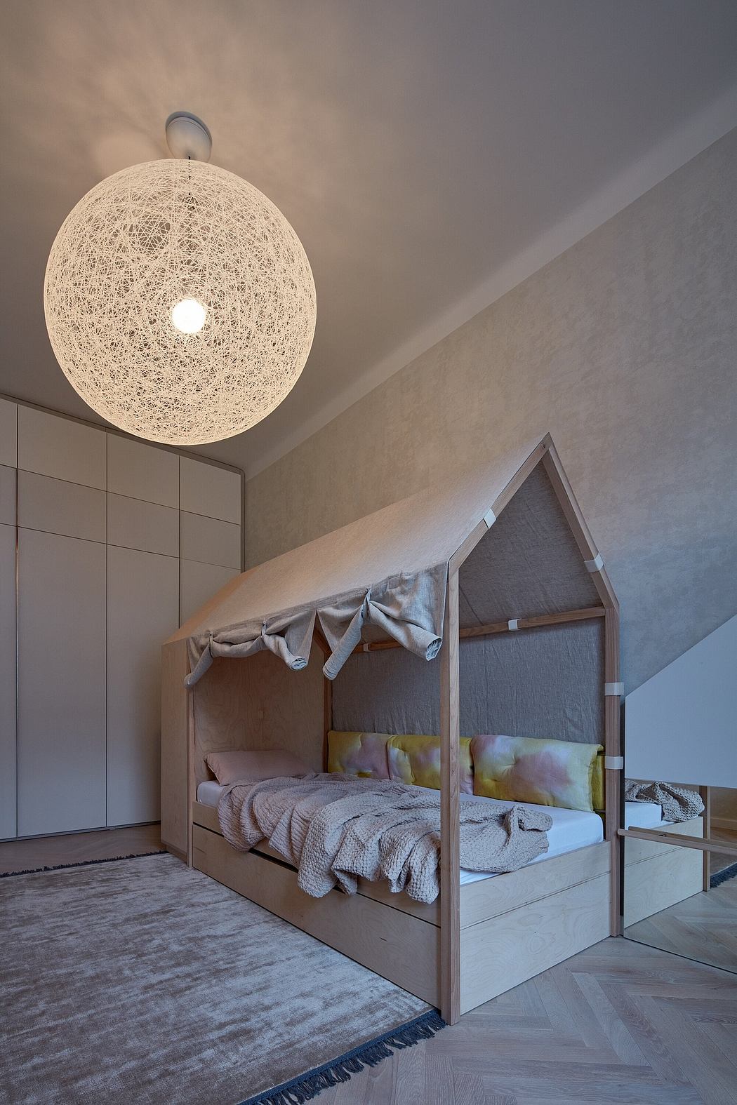 Cozy bedroom with a suspended woven pendant light and a canopy bed on a patterned floor.