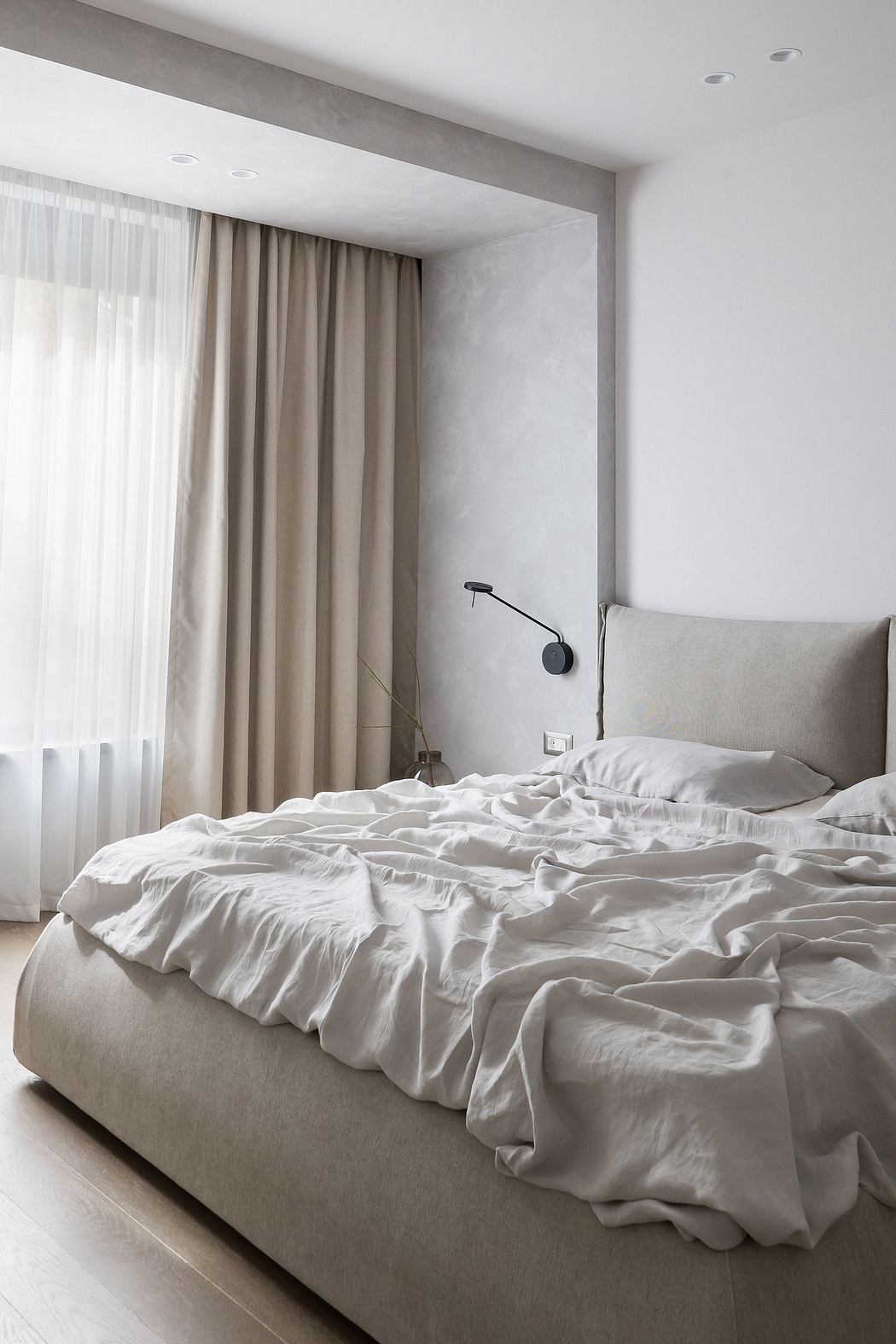 Minimalist, modern bedroom with neutral color palette, curtains, and textured bedding.