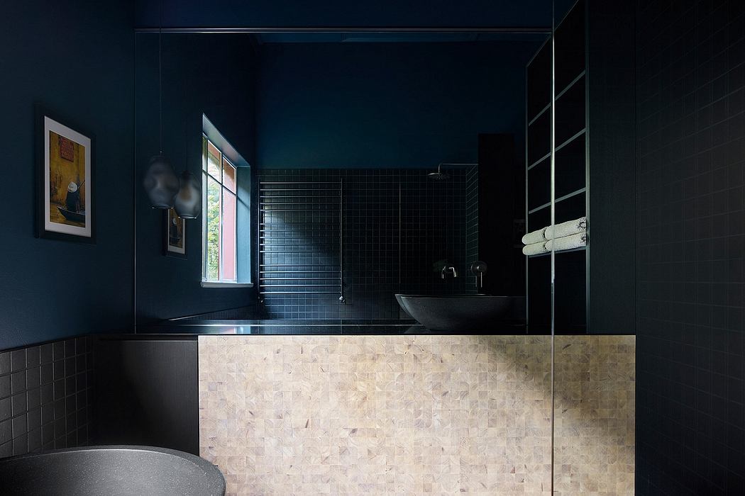 Dark, modern bathroom with black tiles, stone vanity, and minimalist fixtures.