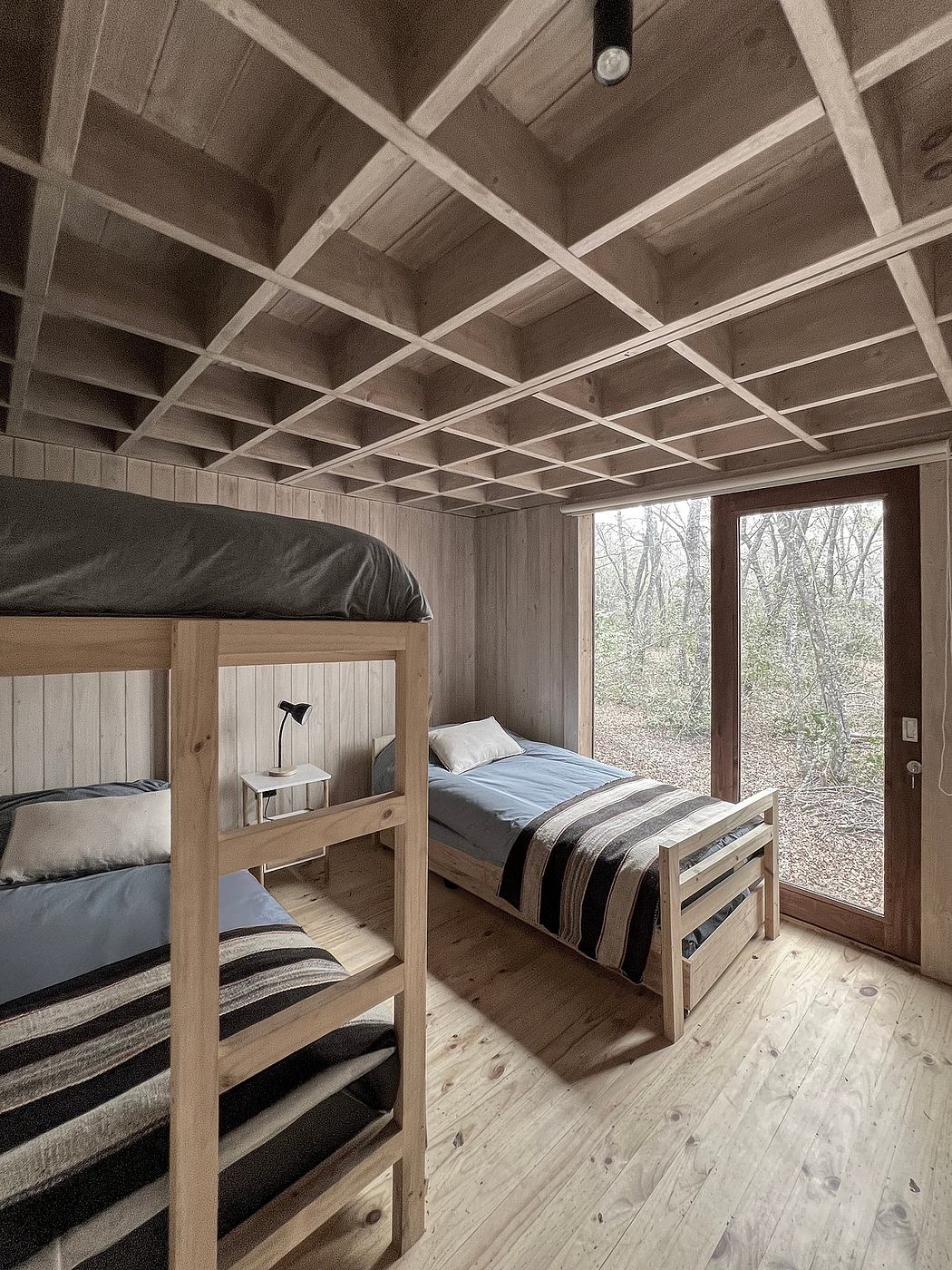 Rustic bedroom with wooden ceiling beams, bunk bed, and large window overlooking nature.