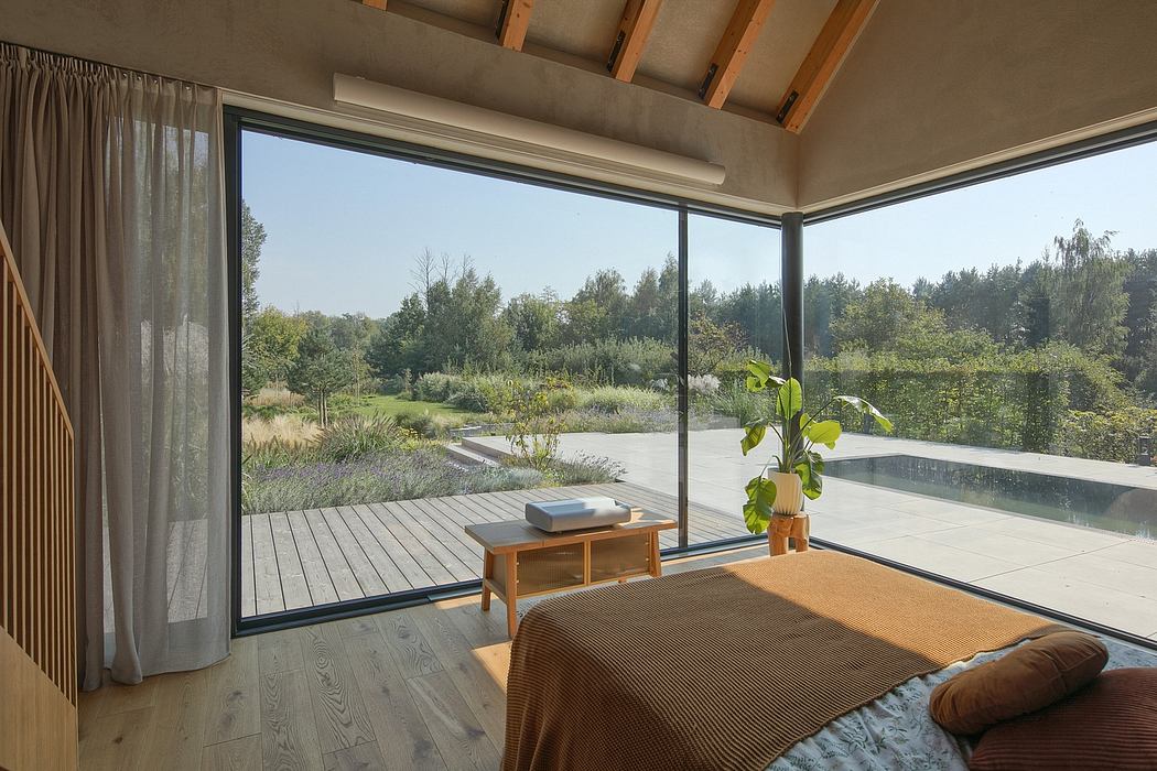 Cozy indoor space with large windows showcasing lush outdoor scenery and a swimming pool.