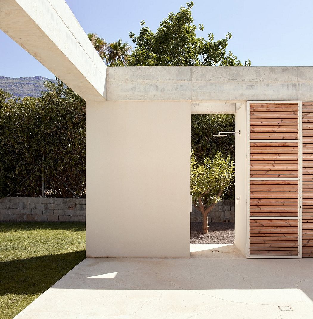A modern concrete structure with wooden paneling, surrounded by lush greenery.
