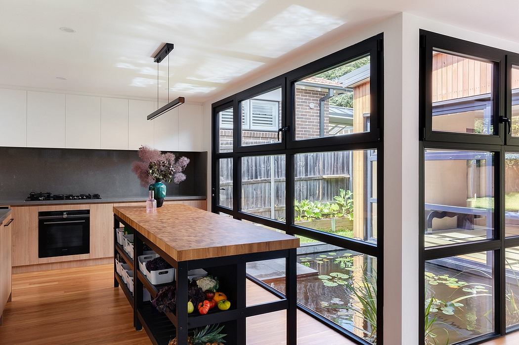 Spacious modern kitchen with sleek black windows, wood island, and dramatic lighting.