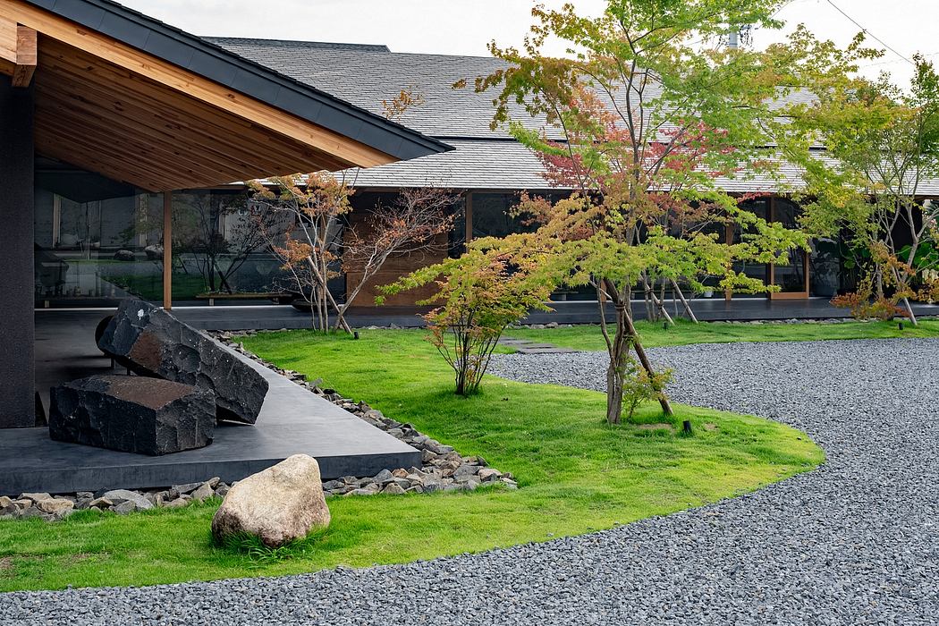 A modern Japanese-inspired home with a peaceful outdoor space, featuring a gravel pathway, lush greenery, and stone accents.