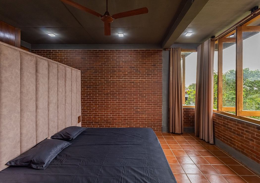 A cozy bedroom with a brick wall, wooden ceiling, and large windows overlooking nature.