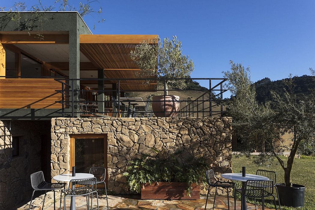 Rustic stone exterior with wooden beams, outdoor seating area overlooking lush landscape.