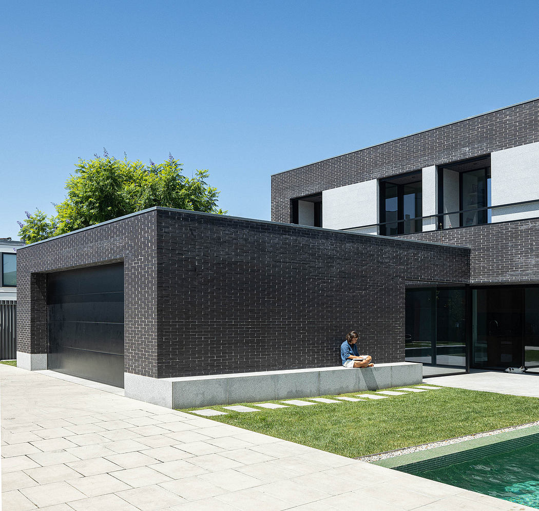 Contemporary residential architecture featuring black brick walls, large windows, and landscaping.
