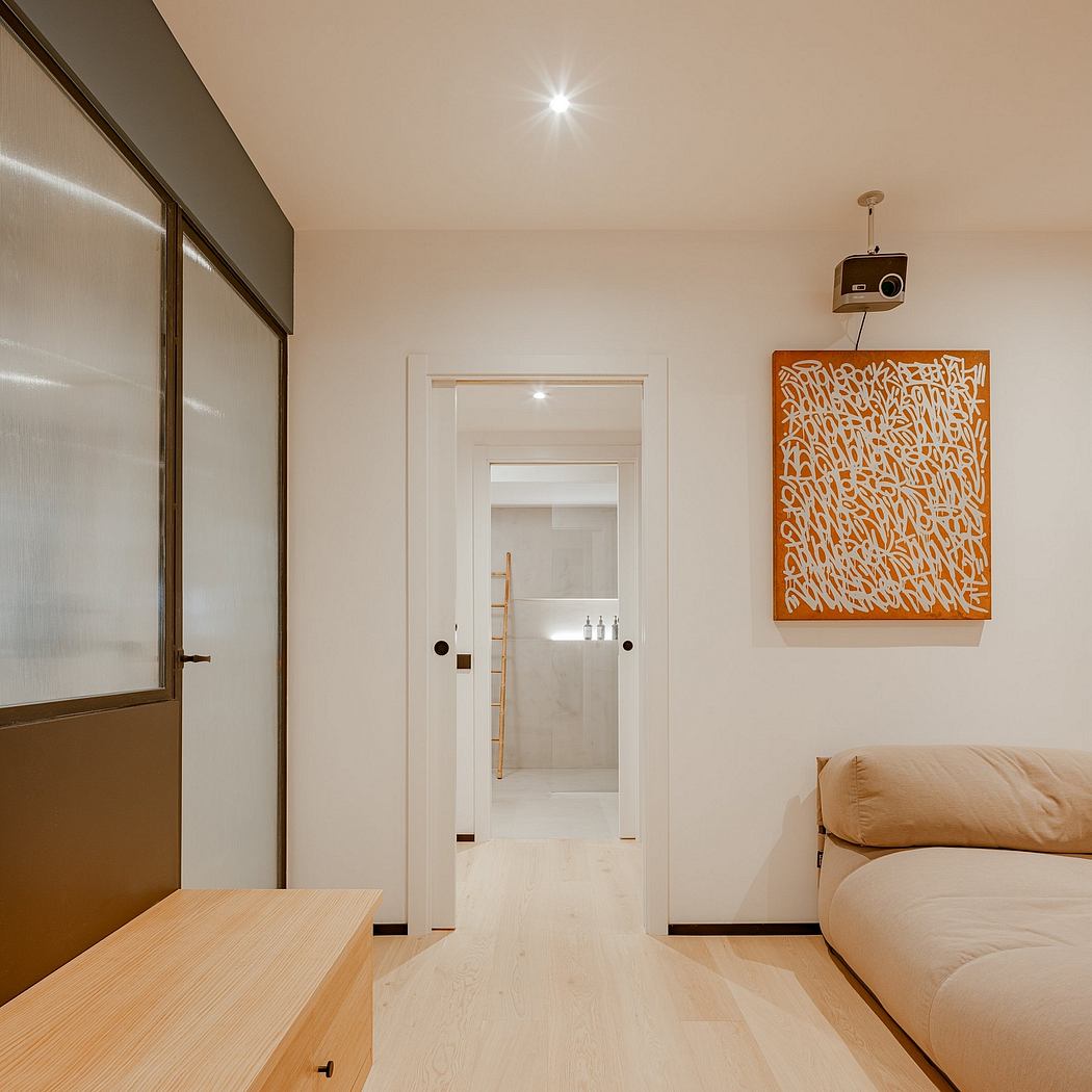 Warm, minimalist interior with wooden floors, white walls, and a vibrant orange artwork.