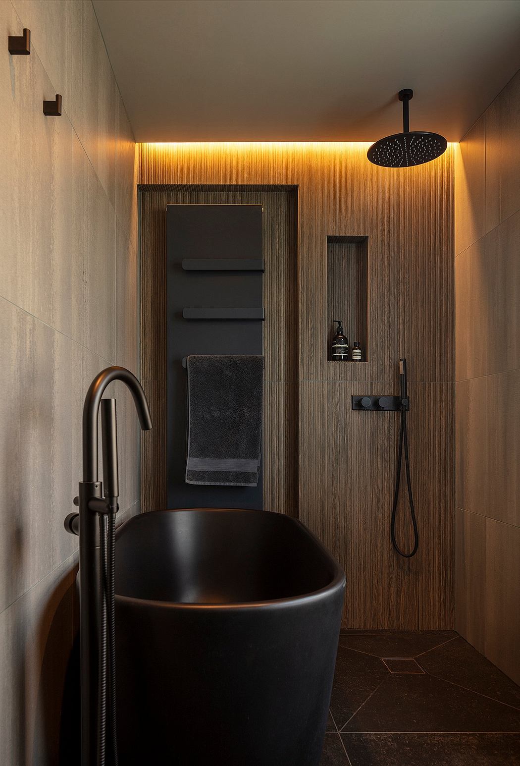 Modern, cozy bathroom with warm lighting, sleek black tub, and wooden accents.