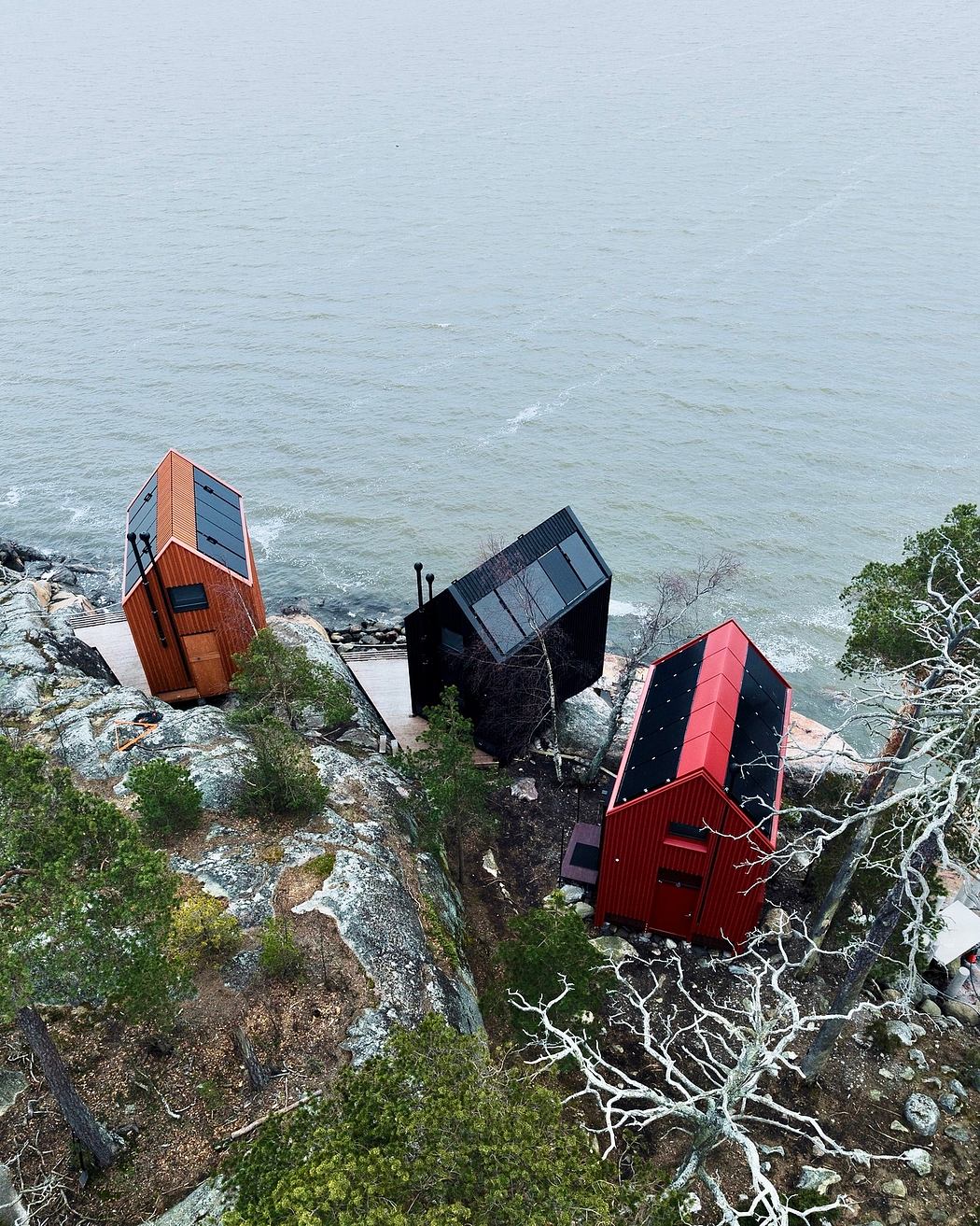 Unusual geometric cabin structures in a natural seaside setting, juxtaposing modern design and landscape.