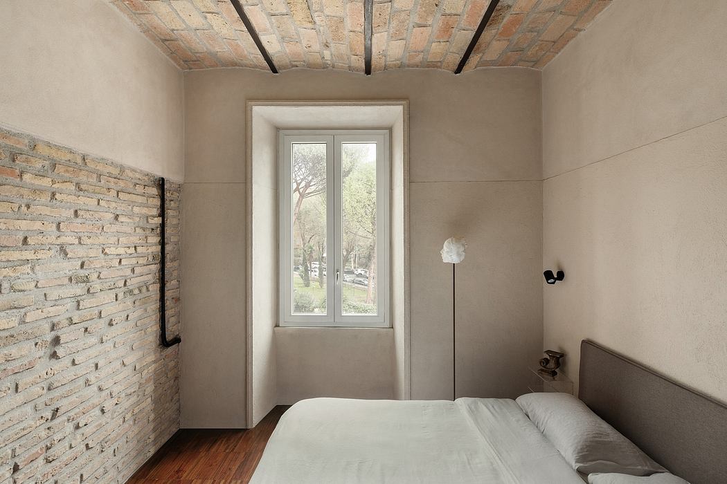 A cozy bedroom with exposed brick walls, large windows, and a minimalist design.