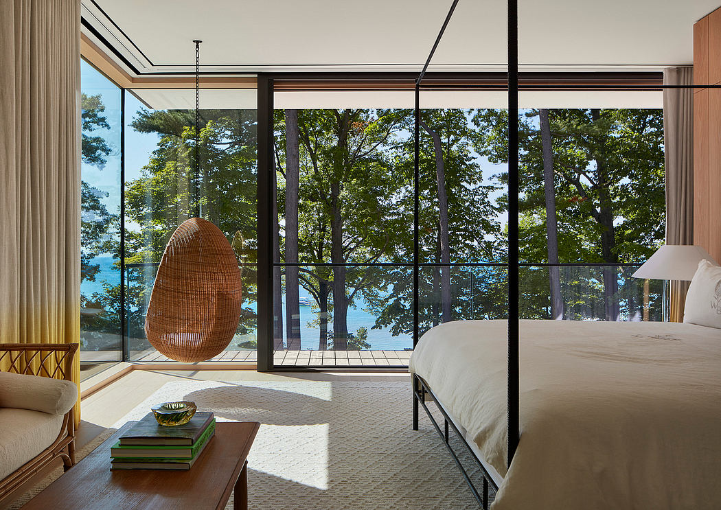 Spacious bedroom with floor-to-ceiling windows, woven egg chair, and wooden furnishings.
