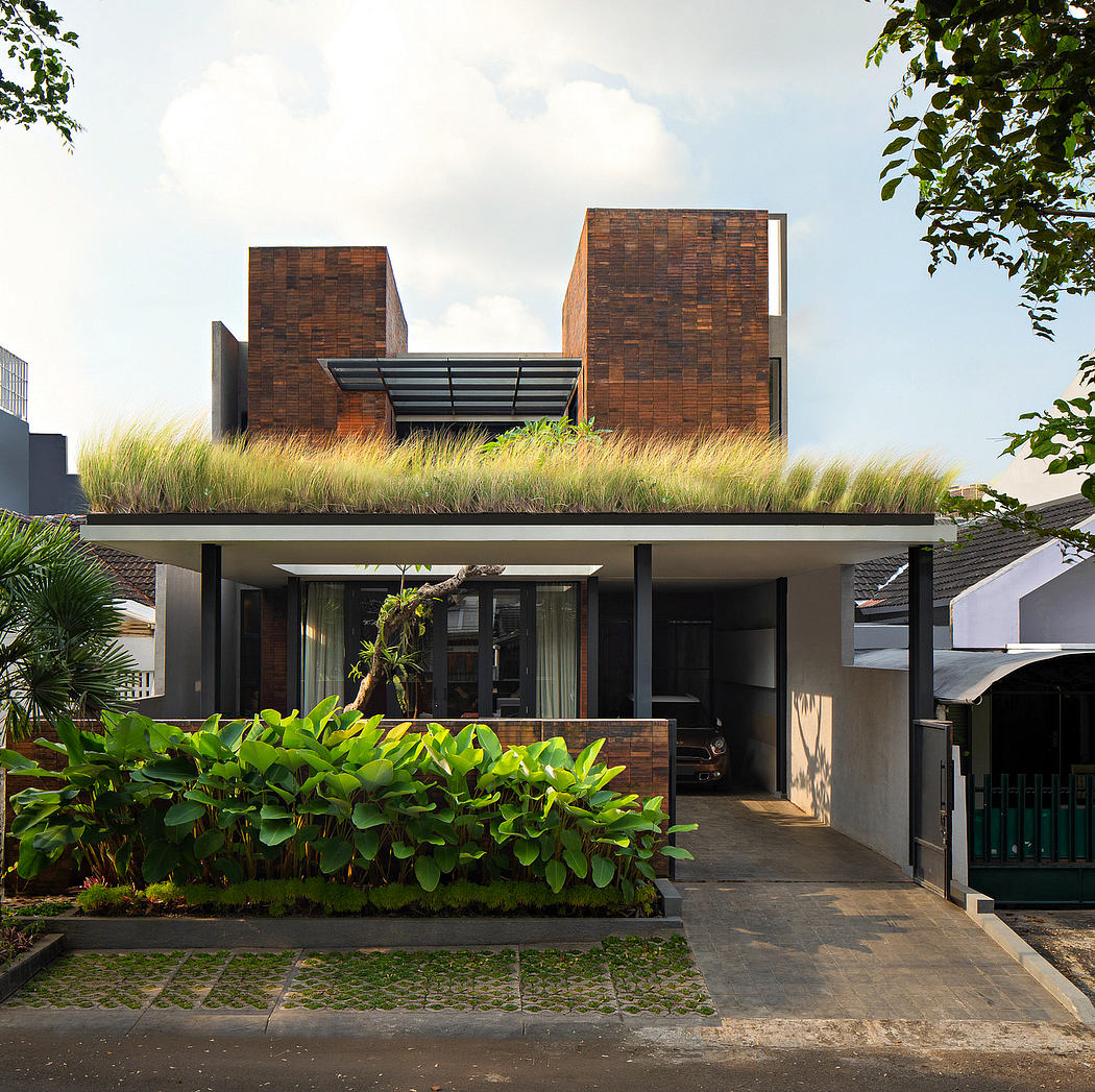 Contemporary brick townhouse with green roof, lush landscaping, and modern architectural elements.