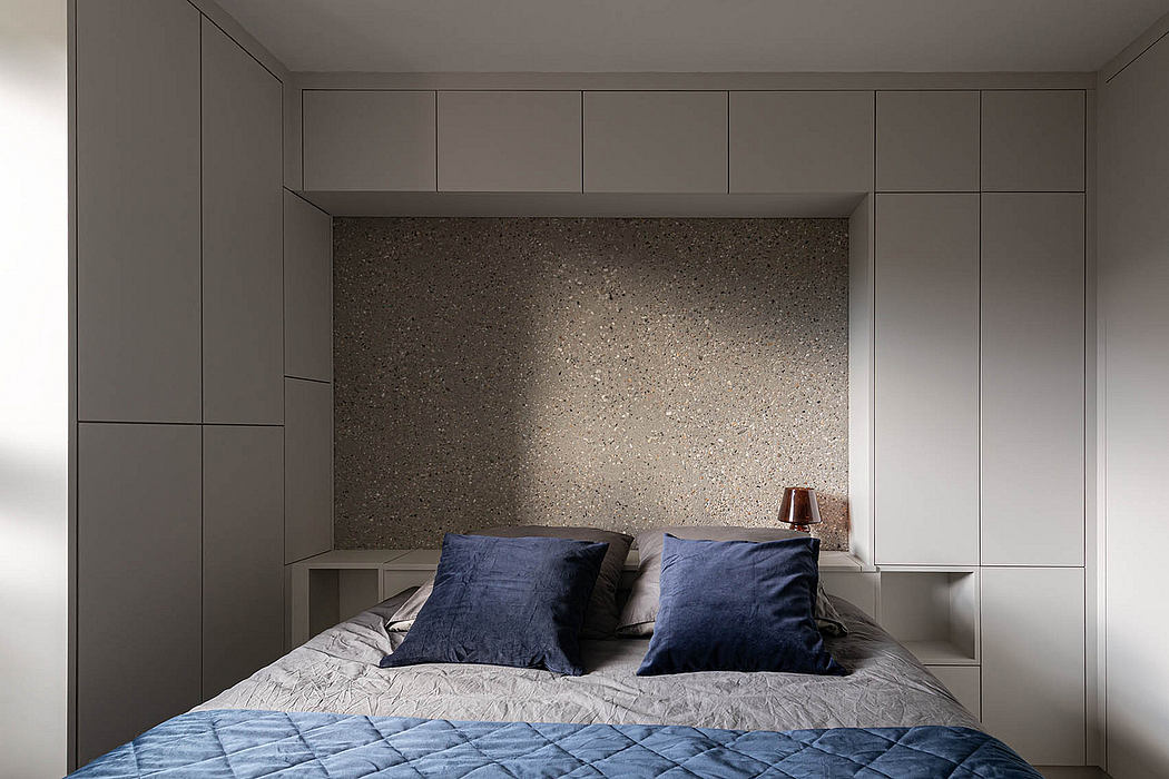 Minimalist bedroom design with built-in cabinetry, textured feature wall, and plush bedding.