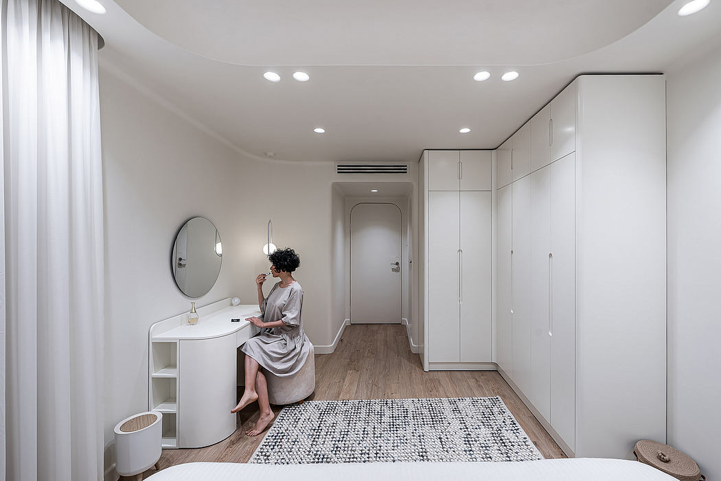 Modern, minimalist bedroom with recessed lighting, built-in wardrobe, and console table with round mirror.