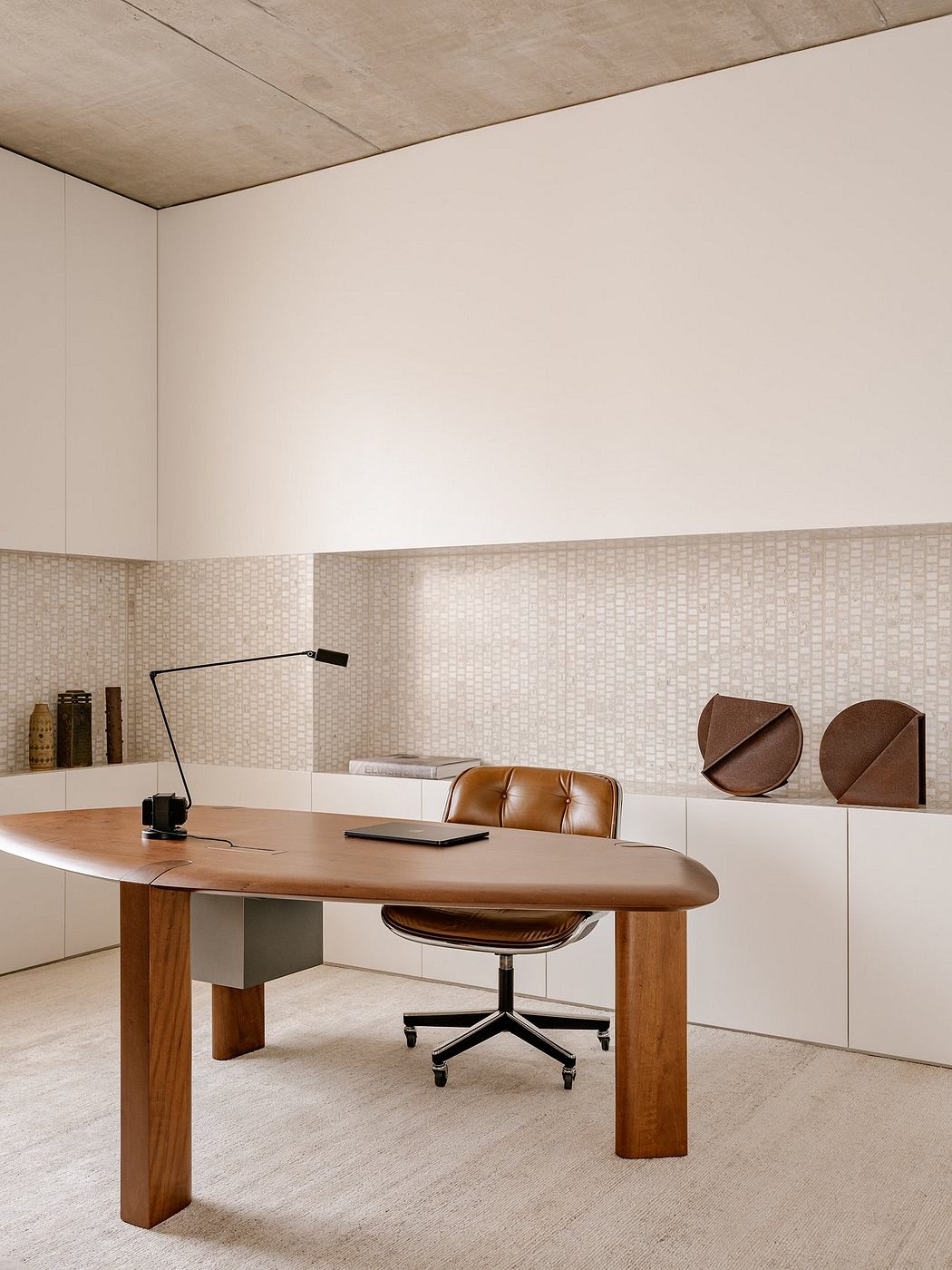 A modern home office with a curved wooden desk, swivel chair, and minimalist wall decor.