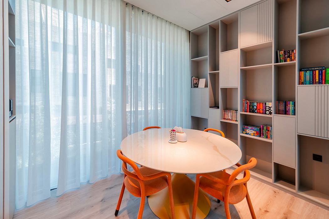 Modern dining area with round table, orange chairs, and built-in shelving unit.