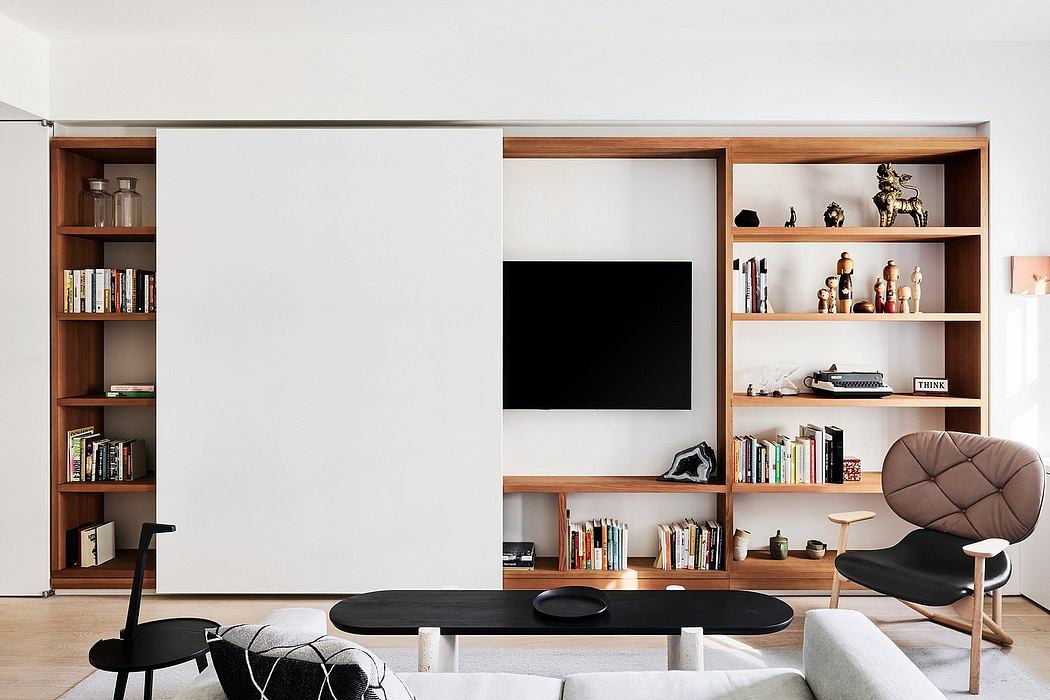 Minimalist living room with built-in wooden shelving, TV, and a cozy armchair.