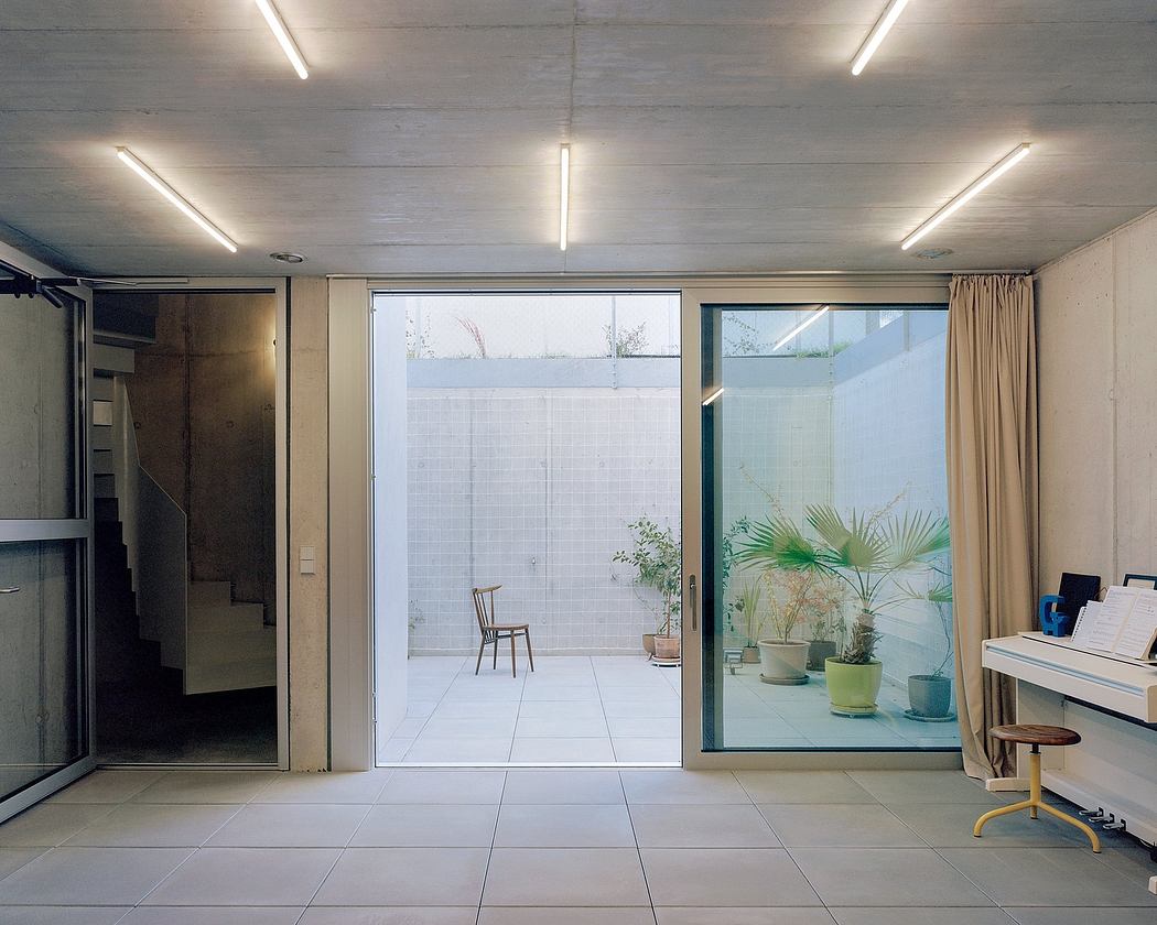 Spacious, minimalist room with large glass doors leading to an outdoor patio with plants.