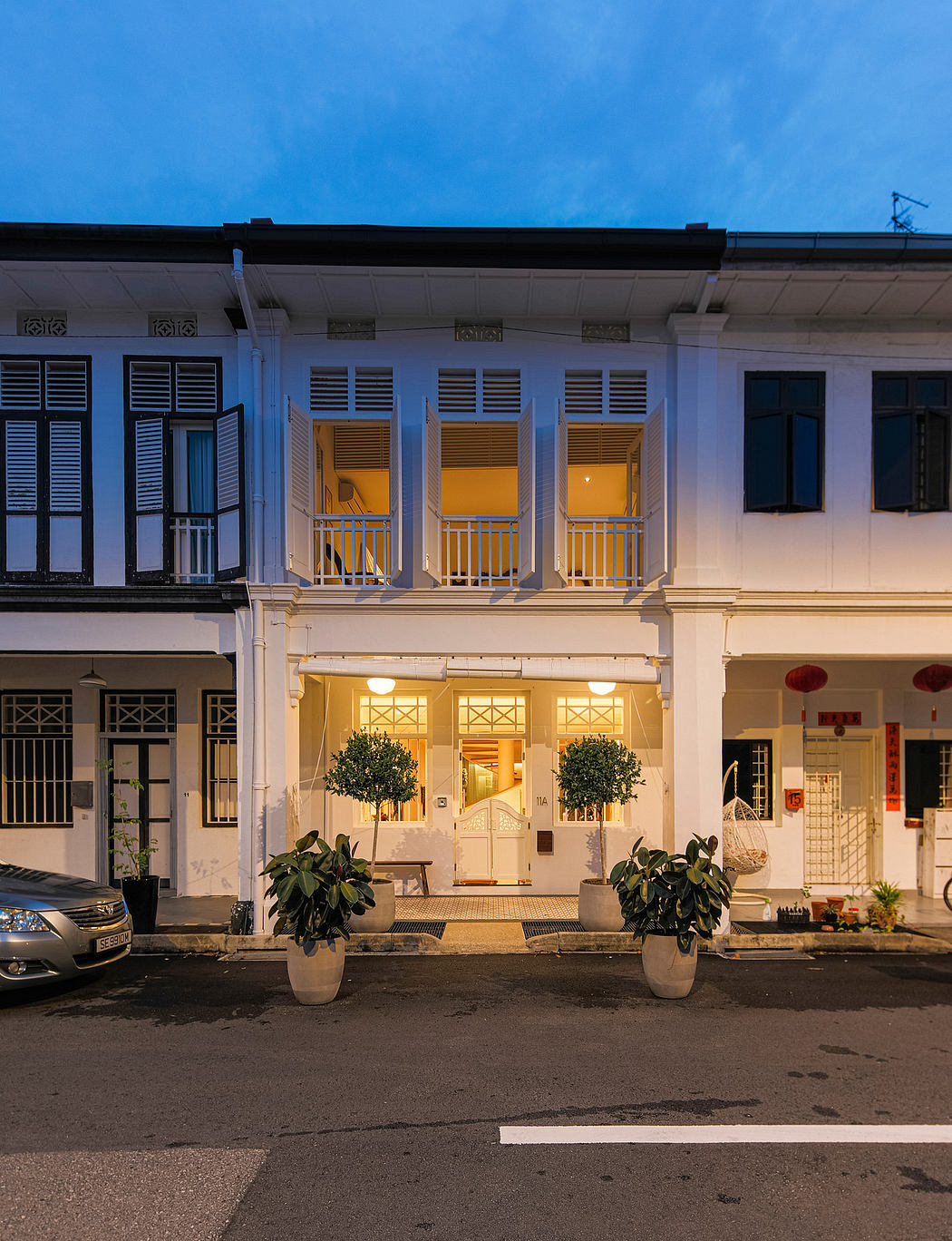 Elegant colonial building with ornate balconies, lush potted plants, and warm lighting.