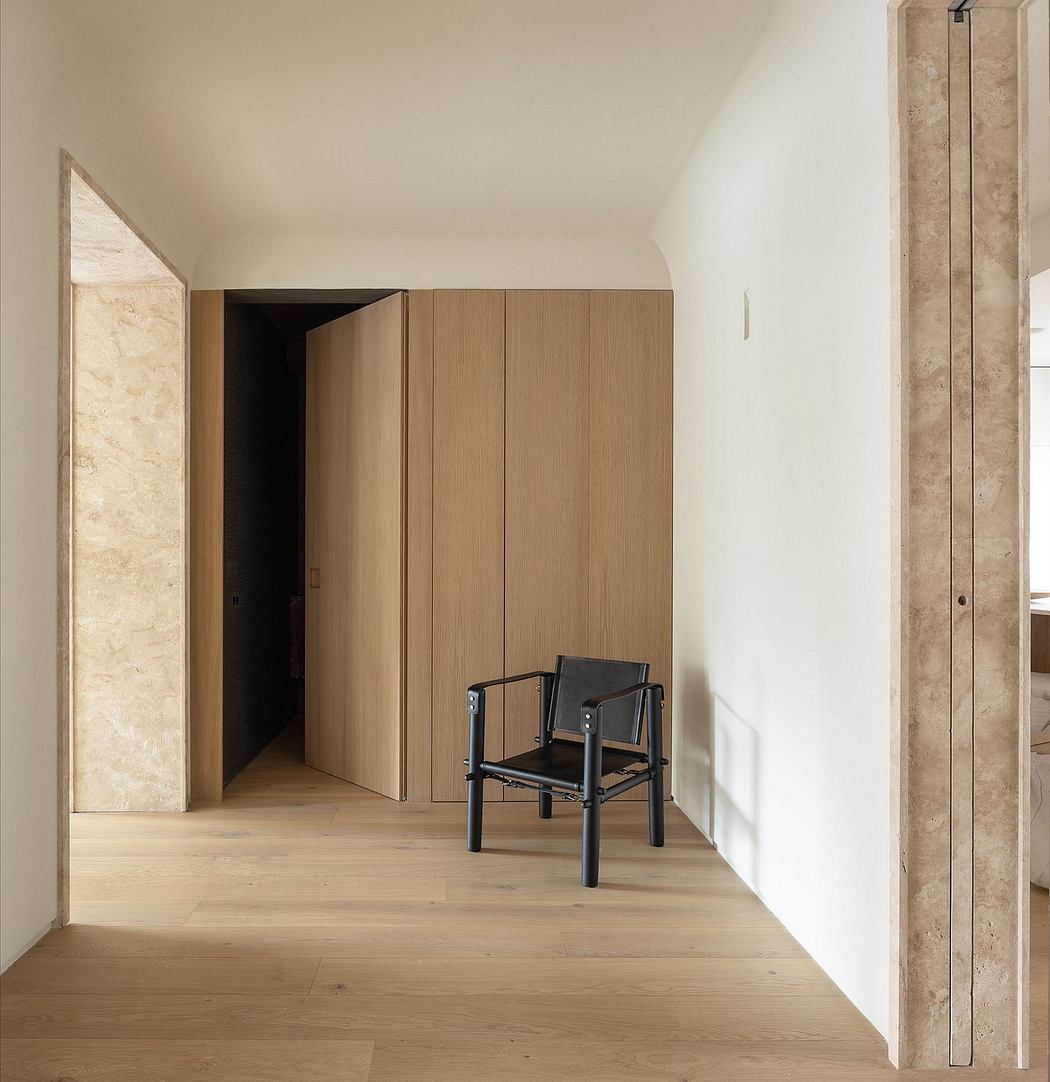Simple, minimalist interior with wooden cabinetry, black chair, and stone accents.