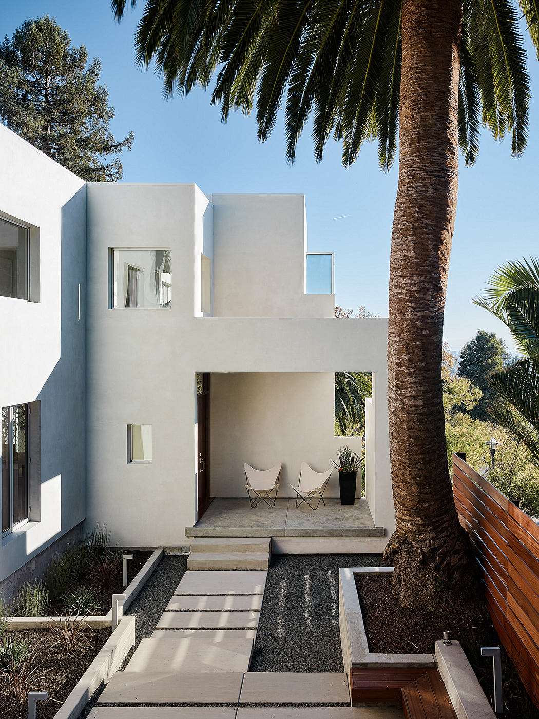Minimalist architectural design featuring geometric forms, clean lines, and lush landscaping.