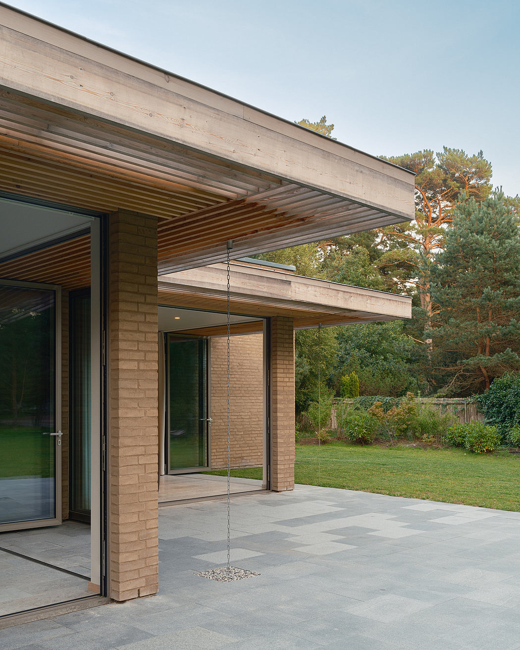 A modern, open-concept home with a sleek, minimalist design and glass walls overlooking a lush garden.